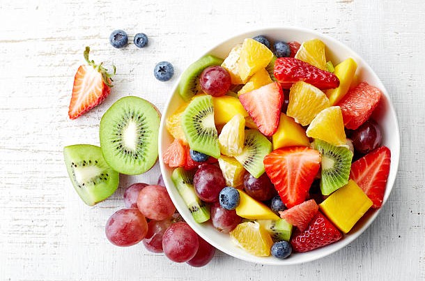 Плодове диета - купа с нарязани пресни плодове - ягоди, манго, киви, боровинки, портокал, грозде
